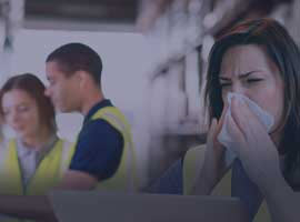 Worker sneezes beside two colleagues
