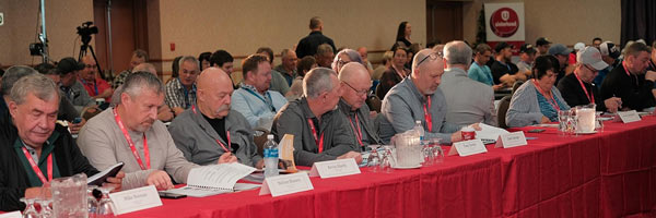 A group of people sitting at a table and rows of people behind