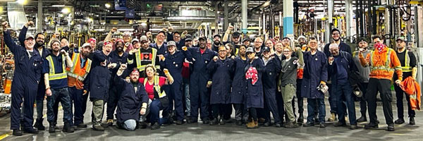 A large group of people in an auto assembly plant.