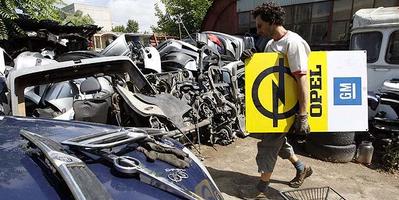 A worker carries an Opel logo sign at a junkyard near Budapest, on June 2, 2009.