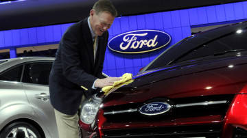 Ford CEO Alan Mulally shines the hood of a Ford Focus.