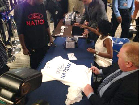 Mayor Rob Ford autographs T-shirts made by Ford Nation supporters after bobbleheads of his likeness that were sold to raise funds for the United Way sold out. 