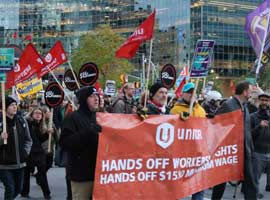 Rally for $15 for fairness group holding a Unifor banner