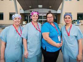 Four smiling nurses wearing scrubs outside of St. Joseph's Hospital in London, Ontario.
