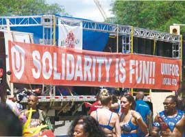 Participants at the 2019 Toronto Caribbean Carnival in Unifor’s section, with red banner in the background.