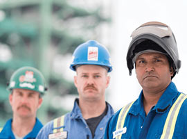 Three men stand in a line wearing personal protective equipment.