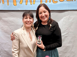 Gina Smoke poses with MP Leah Gazan and a medal.
