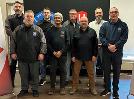Eight men stand beside 'Protect Canadian Jobs' signs 