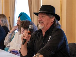 Guy Desforges speaking into a microphone while seated.